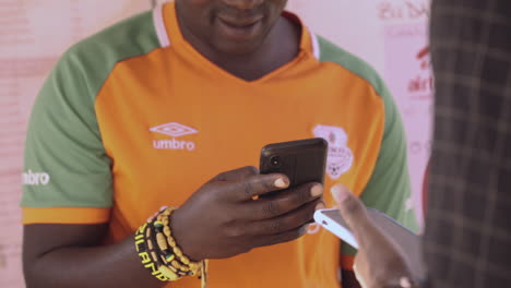 Using-his-cellular-phone,-a-mobile-money-agent-transacts-with-a-customer-at-his-booth-in-the-Zambian-city-of-Lusaka