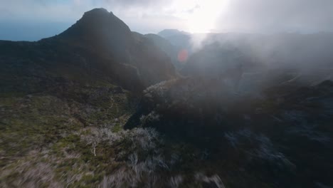 FPV-drone-flying-close-to-the-rocks-through-fog-and-clouds-in-the-mountains-at-Madeira