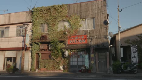 Ivy-covered-building-in-Izumi,-Japan-with-traditional-signage,-bathed-in-golden-sunlight