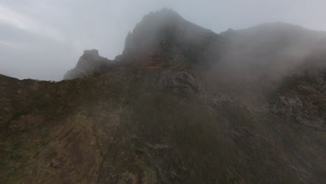 FPV-drone-flying-close-to-the-rocks-through-fog-and-clouds-in-the-mountains-at-Madeira