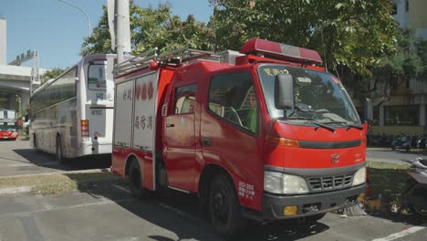 Red-fire-truck-and-white-coach-bus-inTaiwan,-clear-sunny-day,-urban-transportation-scene