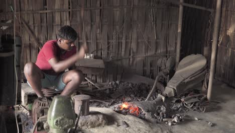 indian-blacksmith-worker-controlling-fire-with-a-bellow-using-a-semi-automatic-rural-machinery