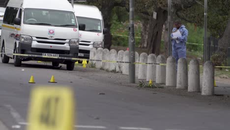 A-police-forensics-investigator-maps-a-drive-by-taxi-shooting-murder-scene-in-Hout-Bay,-Cape-Town,-South-Africa