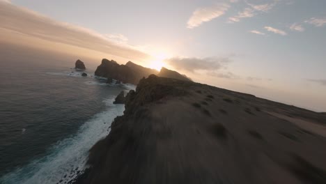 FPV-drone-cruising-on-the-edge-of-the-ridgeline-at-Ponta-do-Rosto-beach-during-sunrise