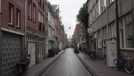Calle-De-Barrio-Vacía-En-Ámsterdam-Con-Bicicletas-Estacionadas-Fuera-De-Las-Casas