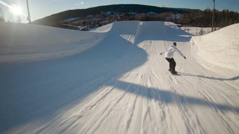 Snowboarder-lands-a-difficult-jump-into-the-sunny-sky---follow-view-in-slow-motion