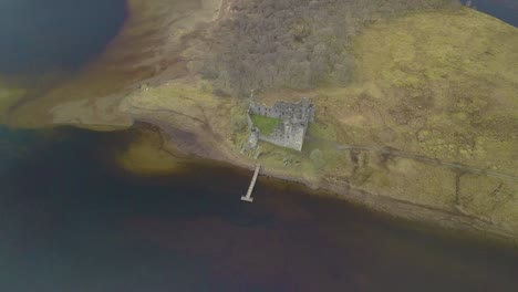 Aerial-top-down-shot-of-famous-kilchurn-castle-and-lake-loch-awe-during-foggy-day,-Scotland