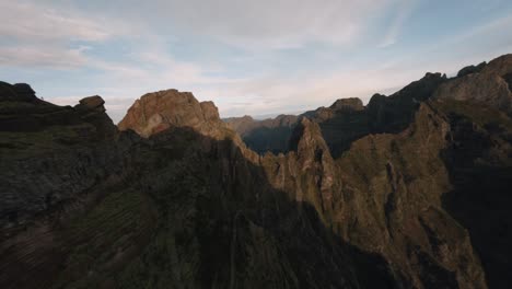 FPV-Drohnenflug-In-Der-Nähe-Der-Madeira-Berge,-Während-Ein-Atemberaubender-Blick-Auf-Eine-Zerklüftete-Bergkette-Sichtbar-Ist,-Wenn-Sanftes-Licht-Auf-Die-Gipfel-Und-Täler-Fällt