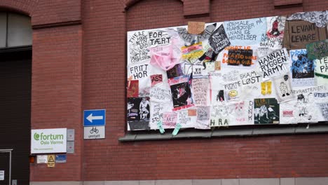 Hand-written-advertisements-and-graffiti-on-the-side-of-a-red-brick-building-in-Oslo,-Norway