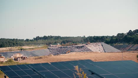 Trucks-working-on-a-waste-treatment-site,-solar-panels-in-the-foreground