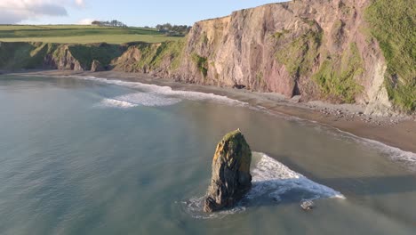 Drone-circling-sea-stack-at-hidden-cove-Copper-Coast-Waterford-Ireland-at-Golden-hour