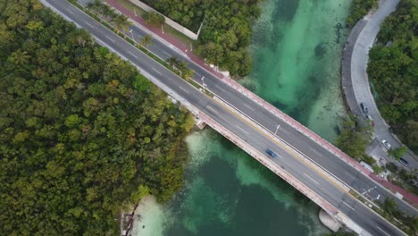 Drone-shot-panning-over-the-Punta-Nizuc-bridge-in-Cancun-Mexico-over-the-Nichupte-lagoon-surrounded-by-a-mangrove-forest-and-emerald-green-river-canal