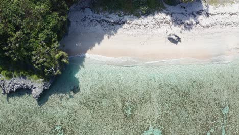 Birdseye-Aerial-View-of-Hidden-White-Sand-Beach-and-Turquoise-Sea-Water