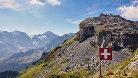 Prado-De-Hierba-Alpina-Alta-Con-Grava-Suelta-Choss-Con-Bandera-Suiza-Sobre-Tabla-Rígida-En-Un-Día-Soleado