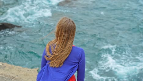 Closeup-shot-of-woman's-back-looking-at-waves-on-a-windy-day,-Tenerife