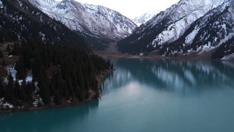 Big-Almaty-Lake-and-snowy-mountains-of-Kazakhstan---panning,-tilt,-drone-shot