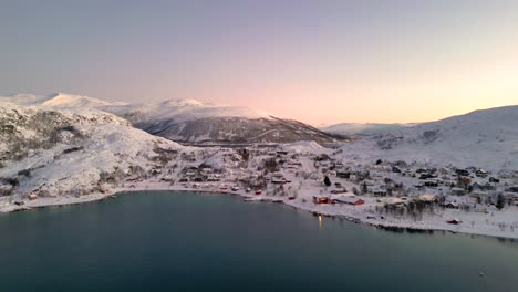 Small-snowy-village-along-Norwegian-fjord-in-winter-season,-Tromso-in-Norway