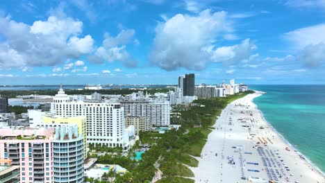 Marvelous-aerial-drone-footage-of-a-sandy-beach-in-Miami,-USA,-slow-rising-pedestal-shot-capturing-a-fascinating-seascape-and-the-tall-buildings-along-it