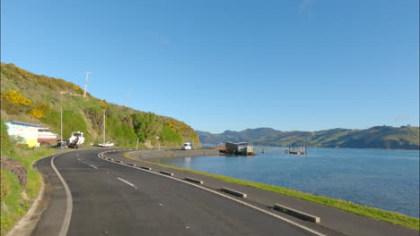 Car's-POV-Driving-Through-Coastal-Road-Along-The-Blue-Sea-In-Dunedin-Peninsula,-Otago,-New-Zealand