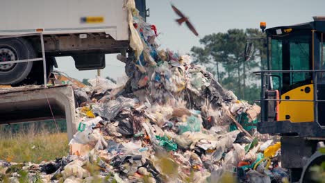Close-up-of-a-dump-truck-dumping-tons-of-waste-in-an-open-air-landfill