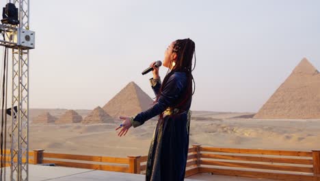 A-singer-performs-on-a-stage-overlooking-pyramids,-Giza-in-Egypt-close-up-shot