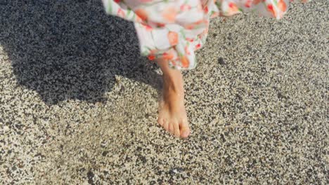 Girl-in-sundress-on-a-vacation,-walking-on-a-beach-with-waves-rinsing-her-feet