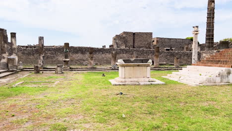 Antike-Ruinen-Von-Pompeji-Mit-Verwitterten-Säulen-Und-Artefakten-Unter-Bewölktem-Himmel,-Schwenk