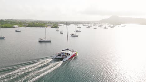Aerial-rear-view-tracking-follows-Irie-Tours-Catamaran-in-Spanish-Waters-boats-anchored-in-bay