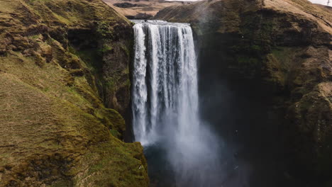 Aerial-pull-back-away-from-the-Skogafoss-waterfall,-sunny-autumn-day-in-Iceland