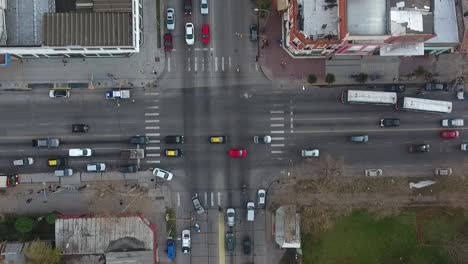 Bustling-city-intersection-with-diverse-vehicles-and-pedestrians,-overcast-Buenos-Aires,-aerial-view