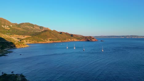 Scenic-drone-view-of-sailing-boats-at-Porto-Flavia-Masua-beach,-South-Sardinia,-Italy