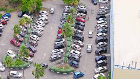 Aerial-trucking-pan-rises-to-reveal-tropical-supermarket-parking-lot-crowded