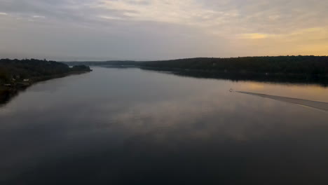 Aerial-footage-of-calm-Kennebec-river,-sunset,-boat-in-distance-moving-on-river