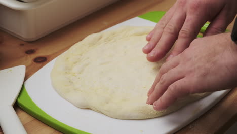 Close-up,-hands-gently-shaping-pizza-dough-into-a-perfect-crust-on-a-cutting-board