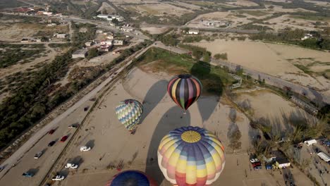 Aerial-view-of-colorful-hot-air-balloon-landing-at-sunset-during-ballooning-festival
