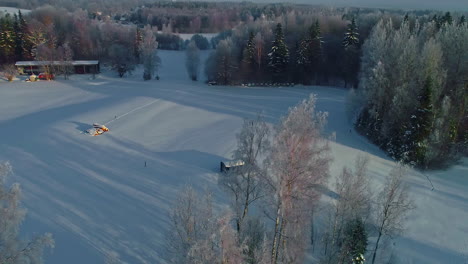 Circular-drone-footage-of-a-snowy-landscape-with-huts-and-some-houses-in-the-distance