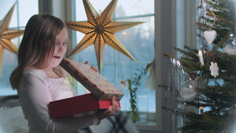 Junges-Mädchen-öffnet-Magisches-Weihnachtsgeschenk,-Gemütliche-Häusliche-Umgebung