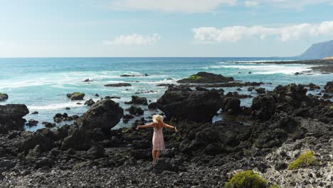 Young-beautiful-woman-enjoys-coastal-rocks-of-Tenerife-island,-back-view
