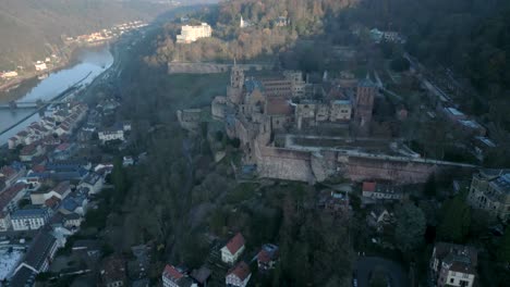 Aerial-view-of-Heidelberg,-a-hillside-town-along-a-river-in-Germany,-the-Heidelberg-Castle-sits-majestically-on-a-mountain-overlooking-the-village
