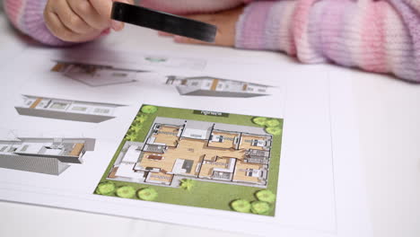 An-individual-looking-at-the-architectural-plan-and-checking-thoroughly-with-a-magnifying-glass
