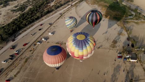 Luftaufnahme-Eines-Farbenfrohen-Heißluftballons,-Der-Bei-Sonnenaufgang-Bei-Einem-Ballonfestival-Auf-Dem-Land-Abhebt