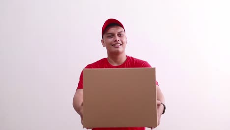 Friendly-young-asian-courier-boy-standing-while-giving-or-offering-cardboard