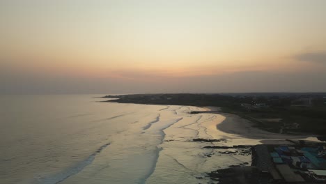 Aerial-shot-viewing-the-sunset-in-Ghana-beach-with-ocean-waves