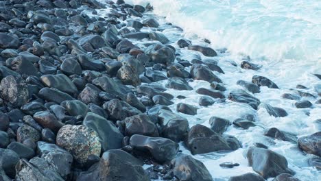 Coastal-rocks-looks-like-polished,-ocean-waves-flow-over,-slow-motion