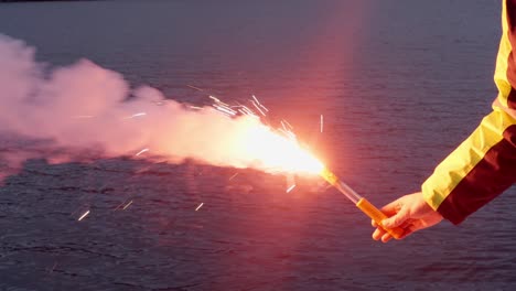 Close-up-of-ship-crewman-holding-emergency-signal-flare,-sea-water-background
