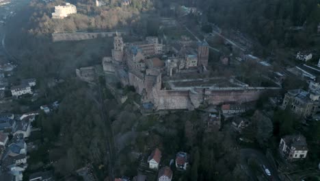 Aerial-view-a-gothic-castle-sitting-atop-a-hill-of-a-remote-village-in-Europe