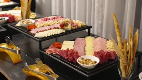 Buffet-table-with-cheeses,-bacon-and-hams,-during-the-banquet-in-the-wedding-celebration-room
