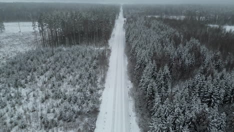 Bird's-eye-view-of-a-country-road-through-snow-covered-pine-forests-in-winter