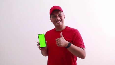 Wow-amazed-young-asian-deliveryman-pointing-green-screen-display-cell-phone