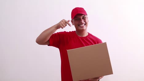 Happy-young-asian-courier-man-holding-cardboard-while-pointing-on-it